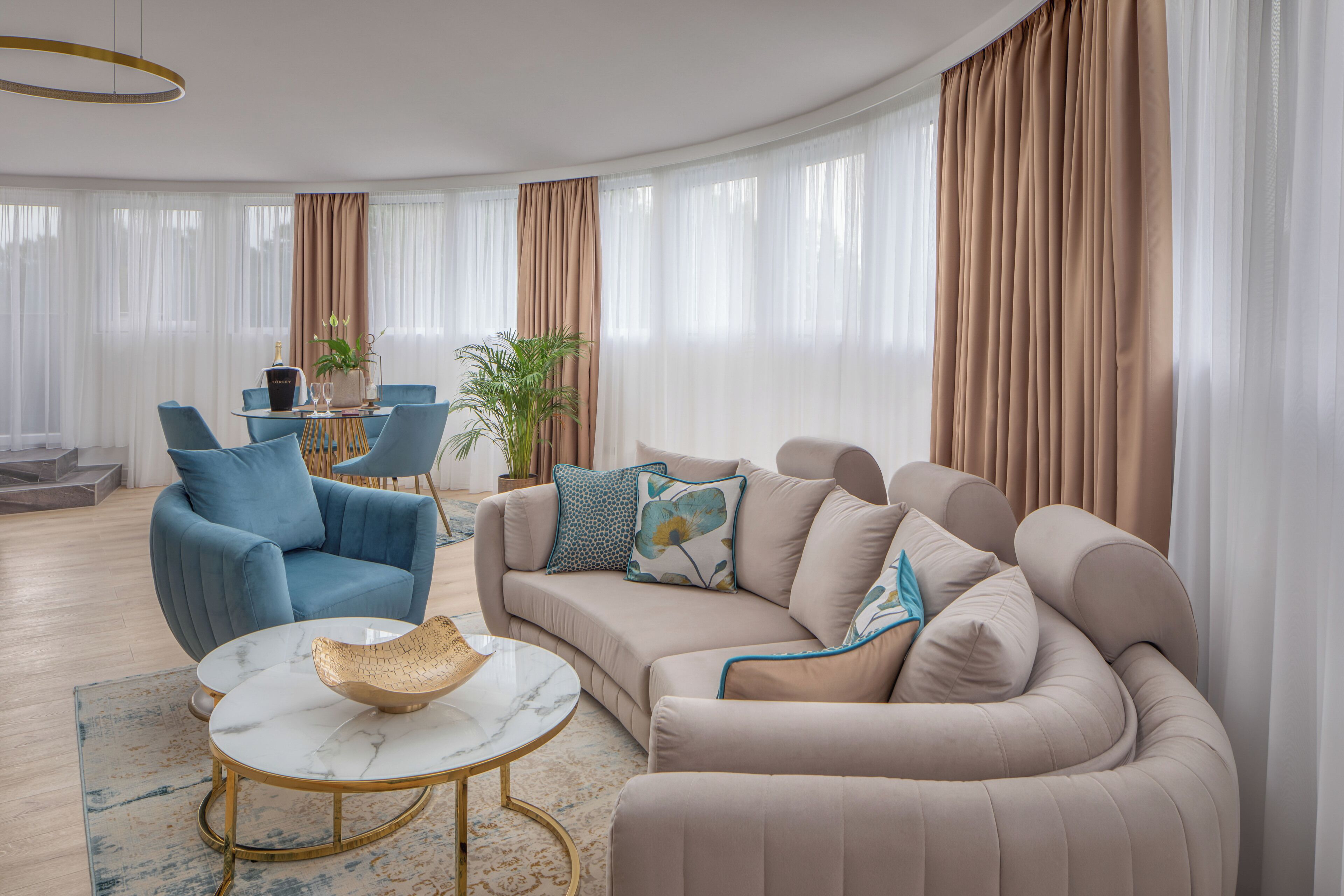 Un soggiorno moderno con un divano beige, una poltrona blu e un tavolino rotondo con una ciotola.