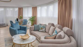 Un soggiorno moderno con un divano beige, una poltrona blu e un tavolino rotondo con una ciotola.