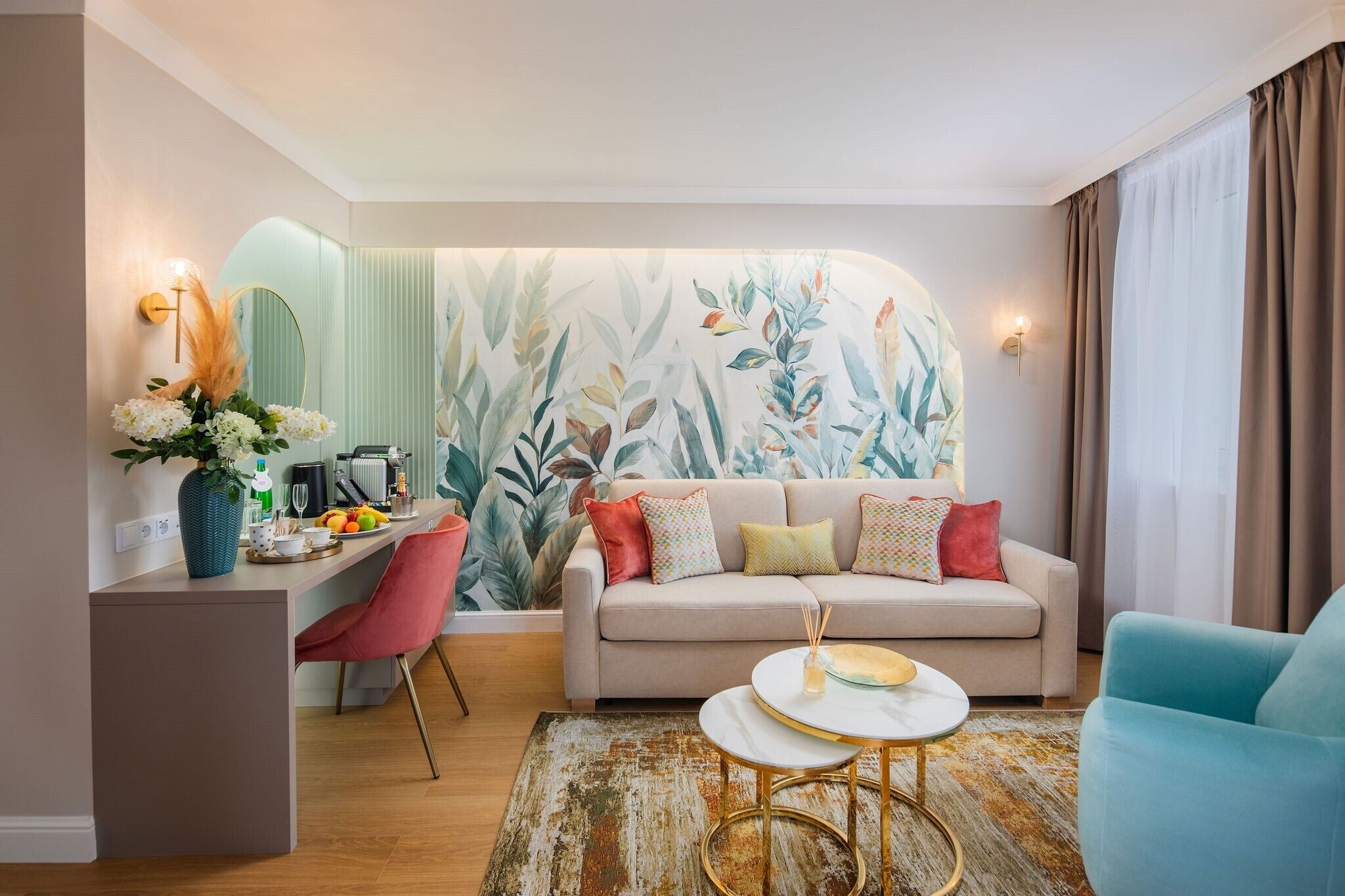 A modern living room with a sofa, a coffee table, and a dining area with a mirror and a vase of flowers.