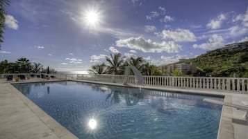 Una piscina al aire libre, sombrillas, sillones reclinables de piscina