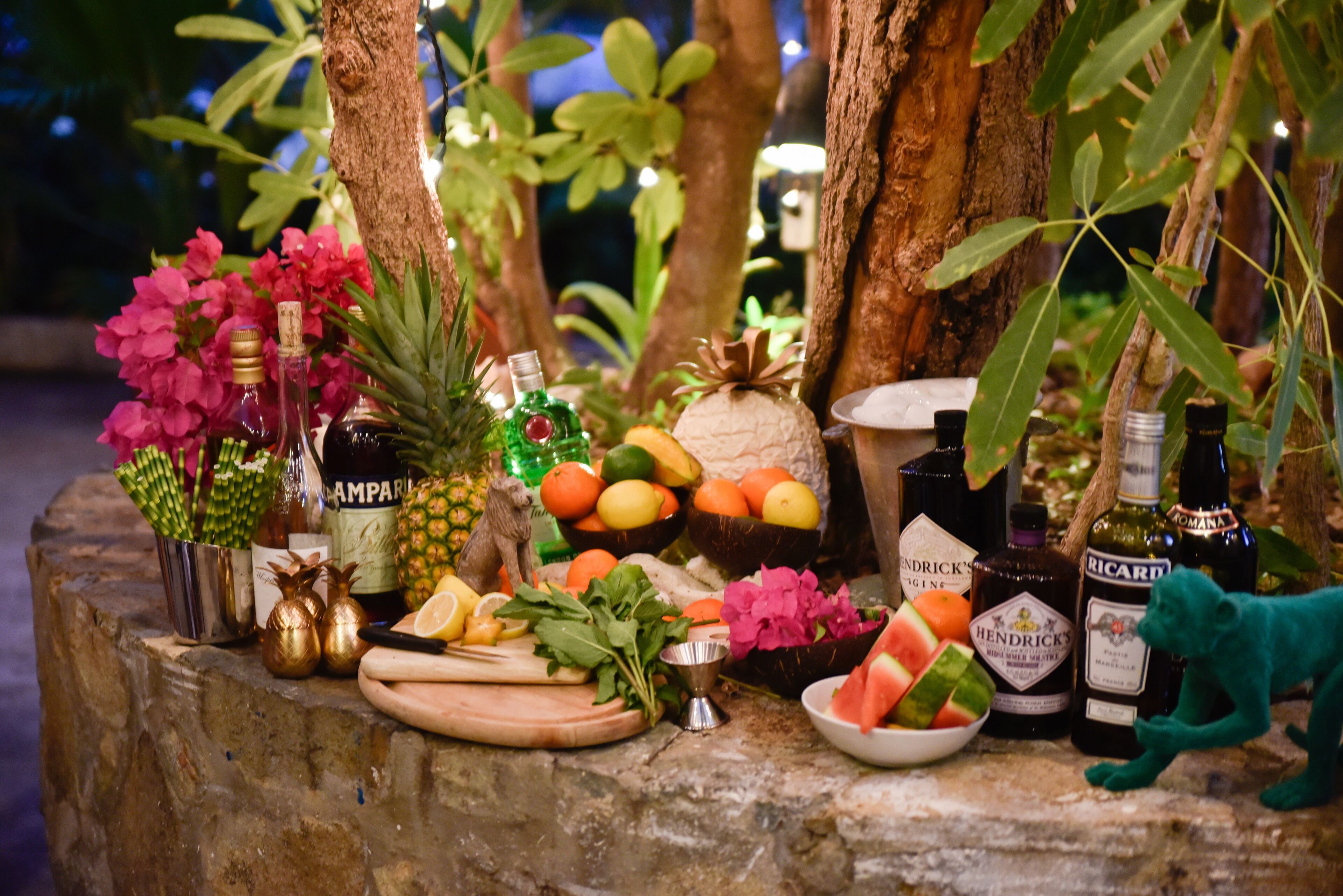 Une table avec différents fruits, des bouteilles et une petite figurine.