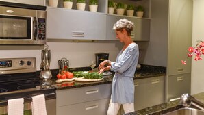 Una cocina moderna con electrodomésticos de acero inoxidable, encimera de granito y plantas en macetas sobre los estantes.