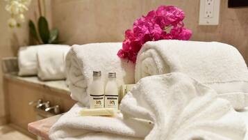 Bathroom amenities are thoughtfully arranged, complete with towels, body lotion, and a fresh bouquet.