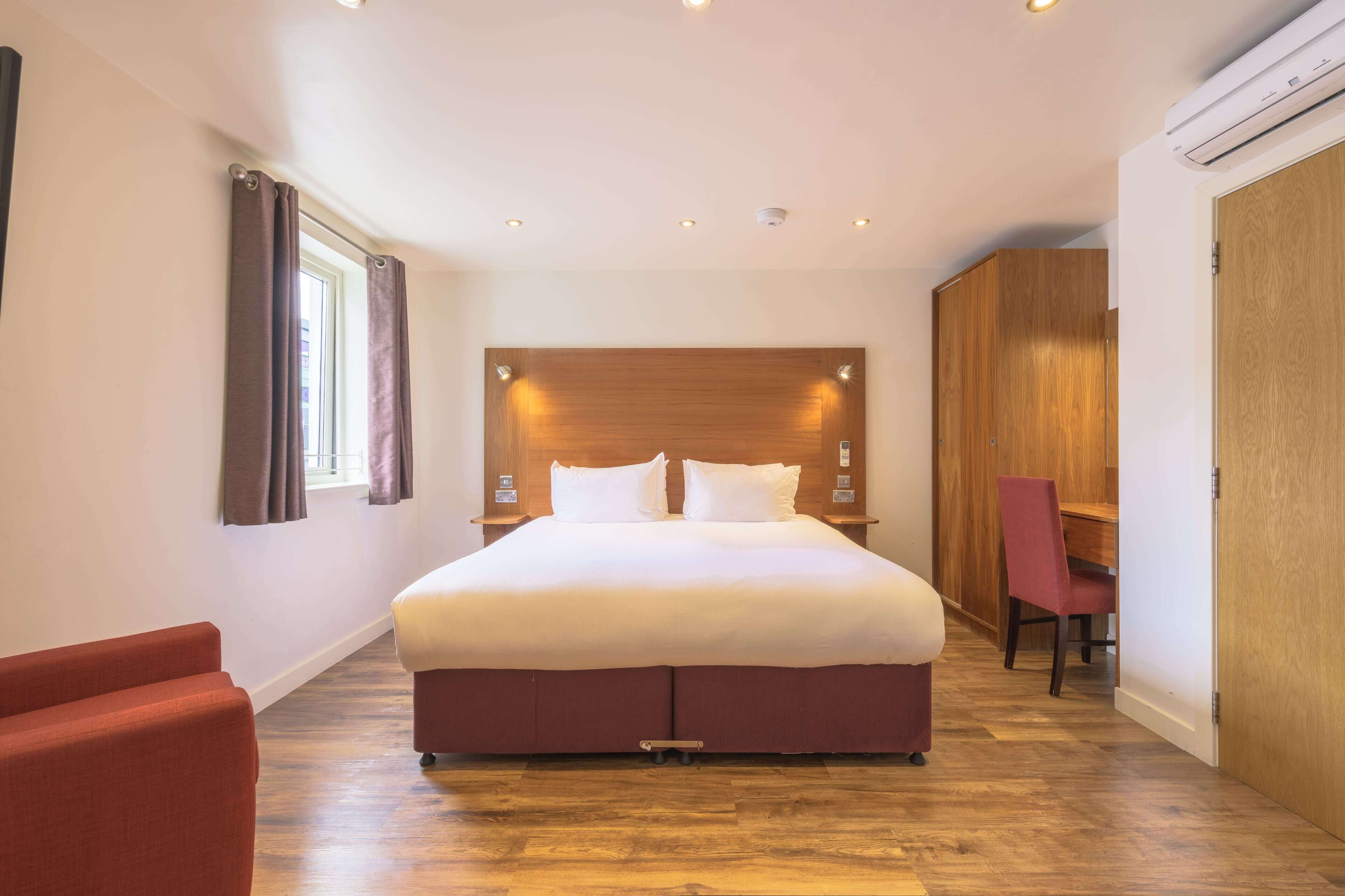 A bedroom with a large bed, a wooden headboard, a desk, and a chair.