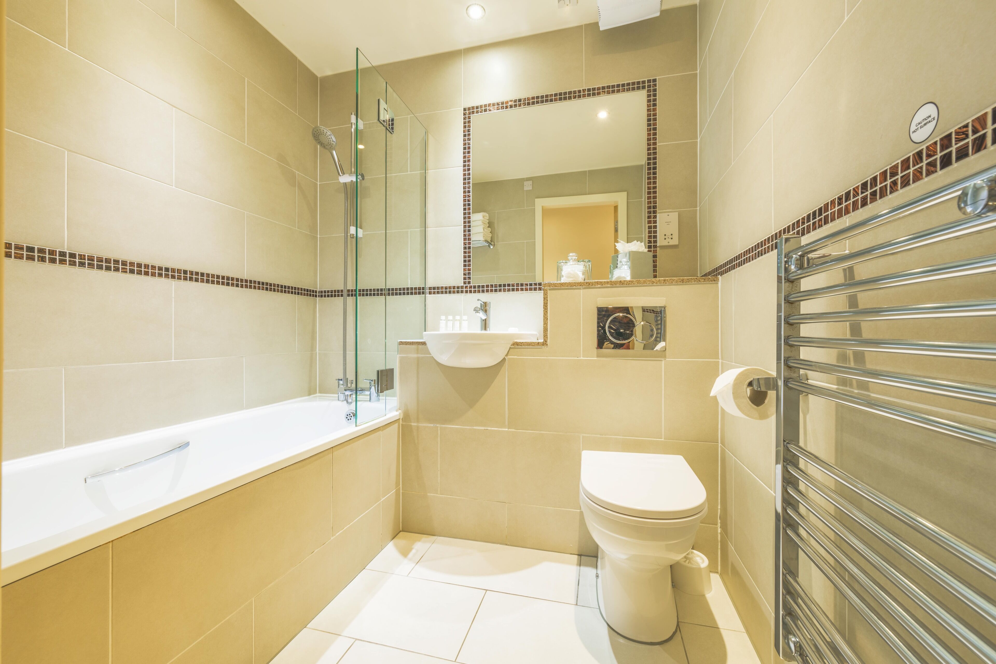 A modern bathroom with a glass-enclosed shower, a white bathtub, a sink, and a toilet.