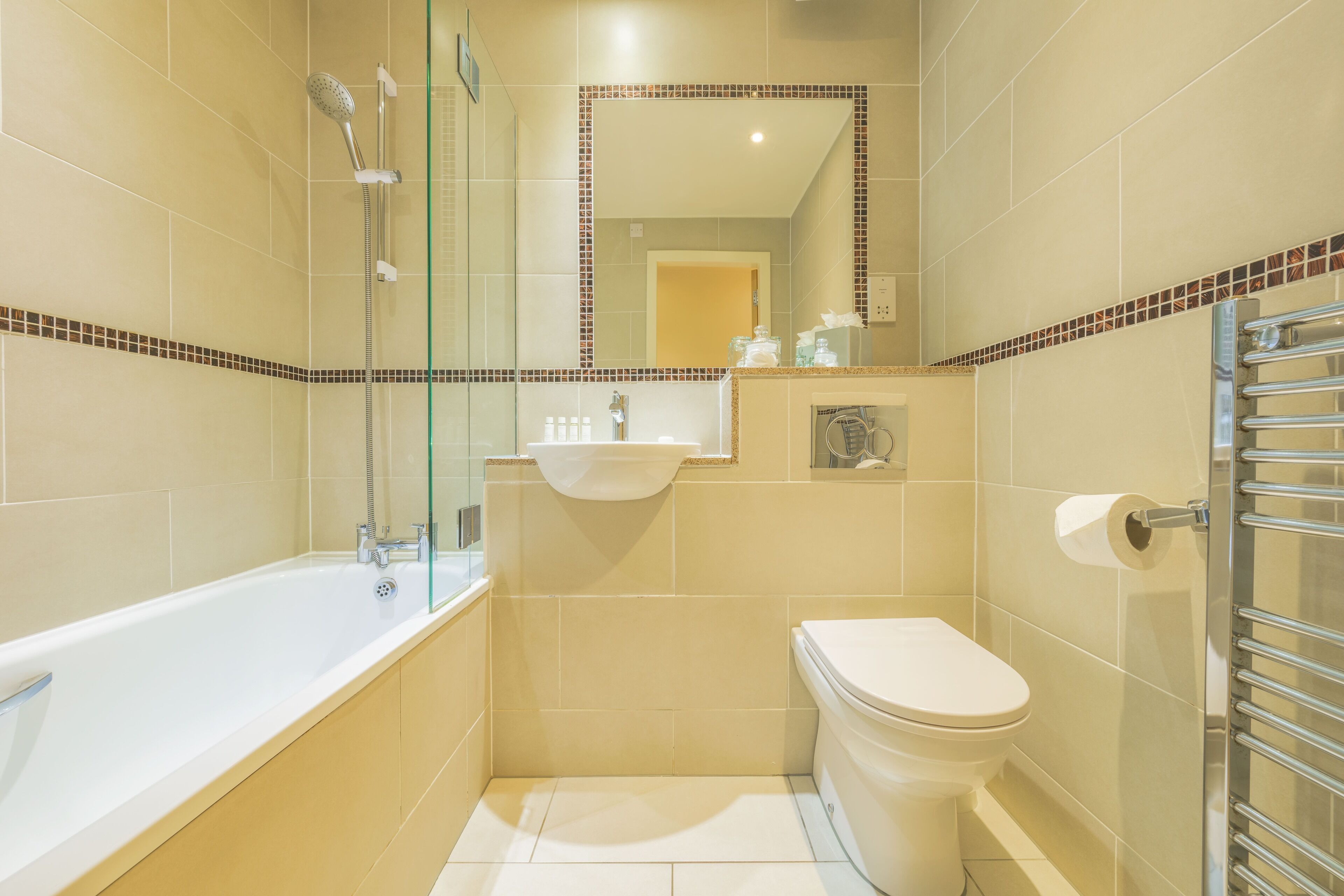 Een moderne badkamer met een douchecabine van glas, een ligbad in het wit en een toilet.