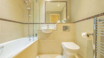 Een moderne badkamer met een douchecabine van glas, een ligbad in het wit en een toilet.