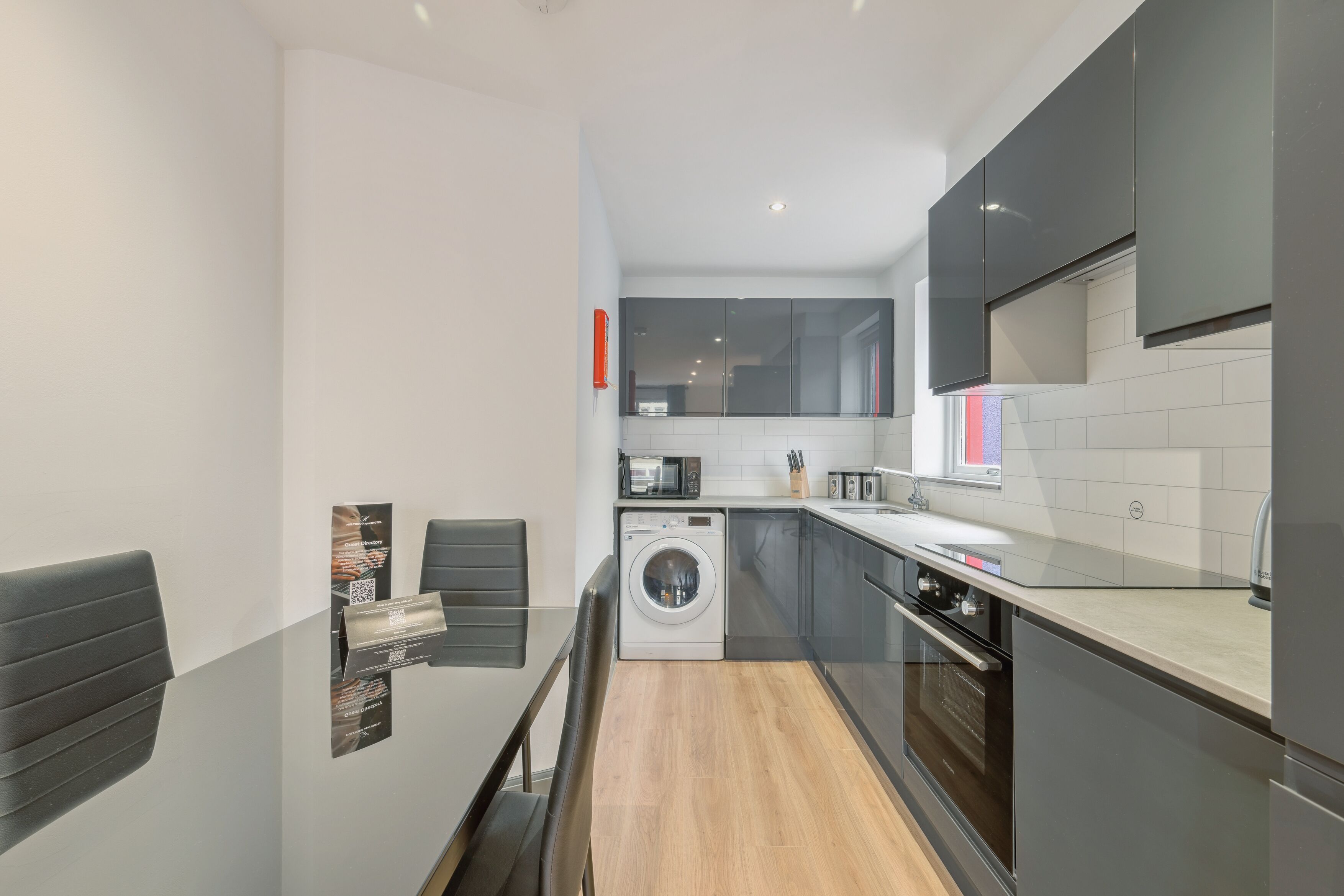 A modern kitchen with a washing machine, a microwave, and a sink.