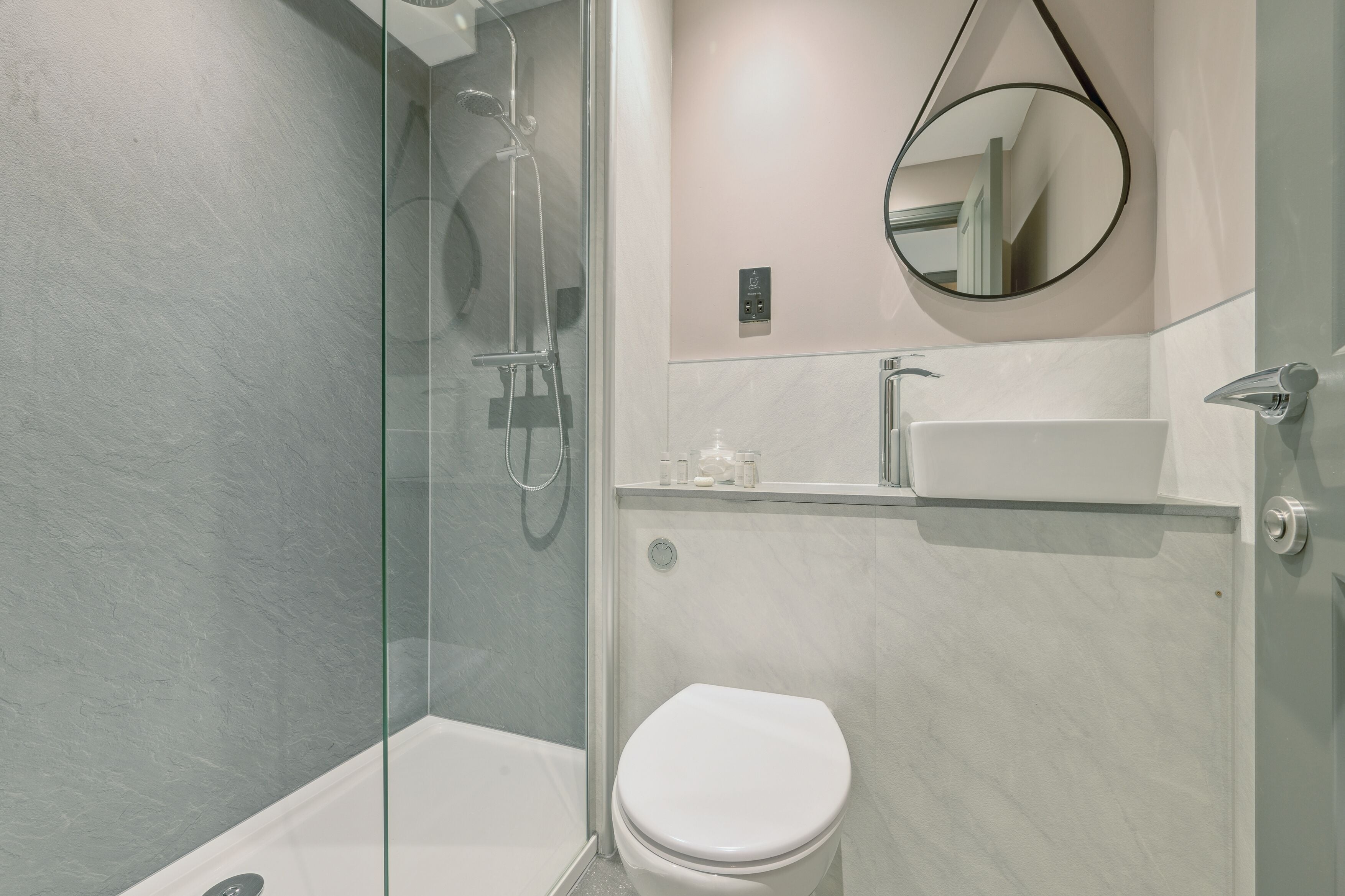 Een moderne badkamer met een douchecabine van glas, een wit toilet en een wastafel met spiegel.