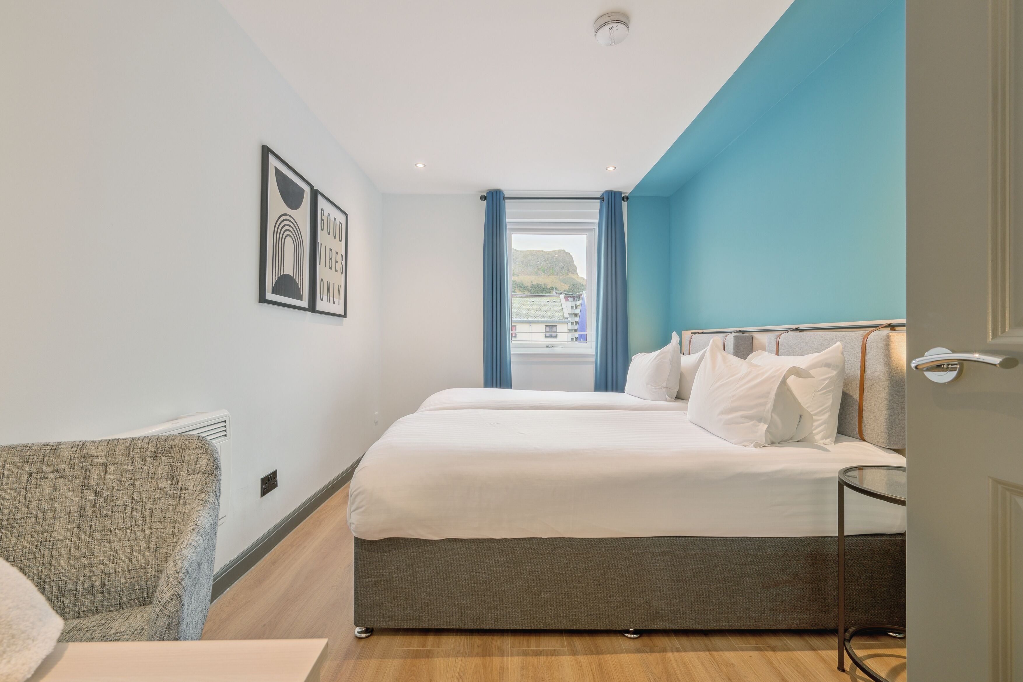 Habitación de hotel moderna con una cama grande, una silla y vistas al exterior.