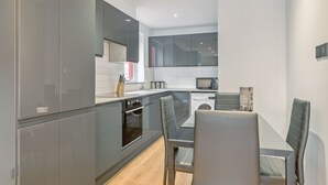 Een moderne keuken met grijze kastjes, een inbouwoven, een magnetron en een wasmachine.