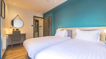 Una habitación de hotel con dos camas, un escritorio, una silla, un espejo y una puerta.