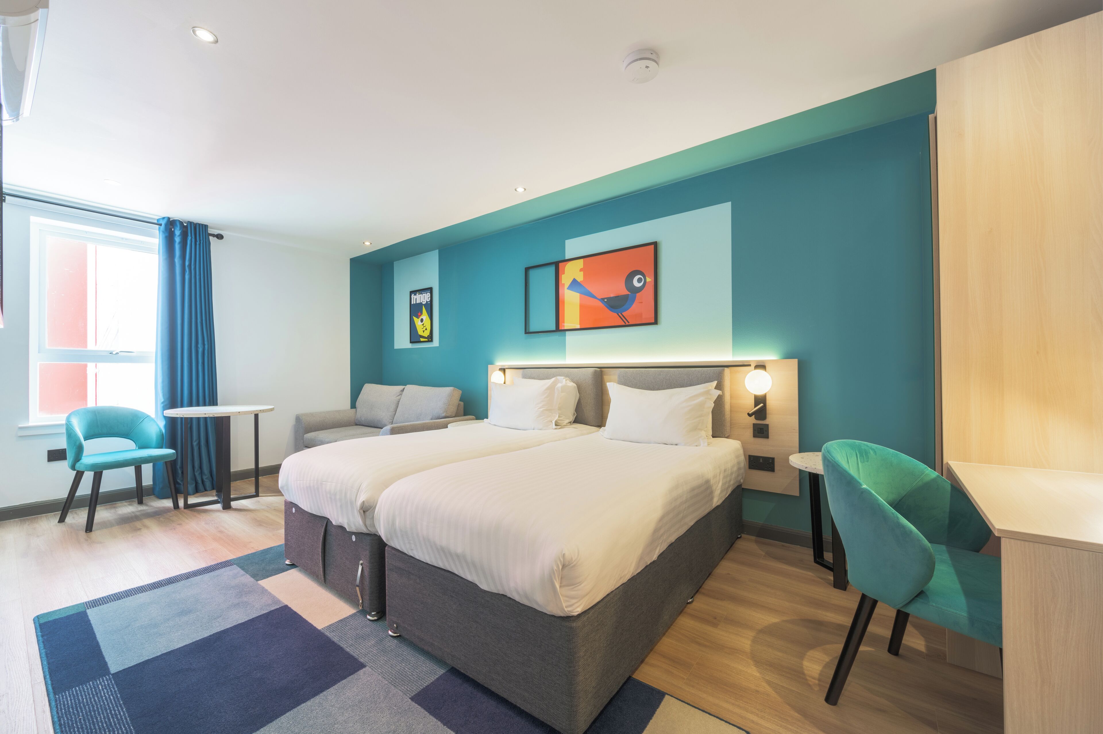 Una habitación de hotel moderna con una cama grande, dos mesitas de noche, un escritorio y una silla.
