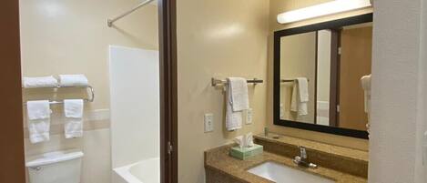 A hotel bathroom with a toilet, sink, and mirror.
