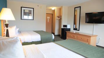 A hotel room with two beds, a TV, a dresser, and a lamp.