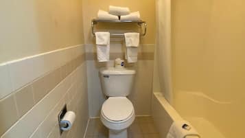 Un baño pequeño con inodoro, toallero con toallas, dispensador de papel higiénico y bañera.