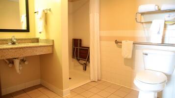 A bathroom with a sink, mirror, shower, and toilet.