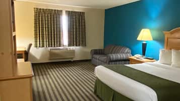 A hotel room with a bed, a chair, a desk, a lamp, and a window with curtains.