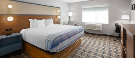 Ein modernes Hotelzimmer mit einem großen Bett, Nachttischen, einem Schreibtisch und einem Sessel.