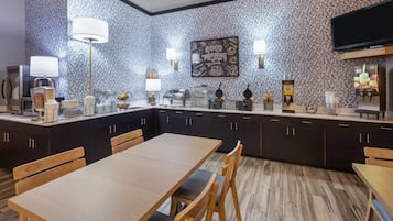 A modern kitchen with dark cabinets, a wooden dining table, and a breakfast bar.