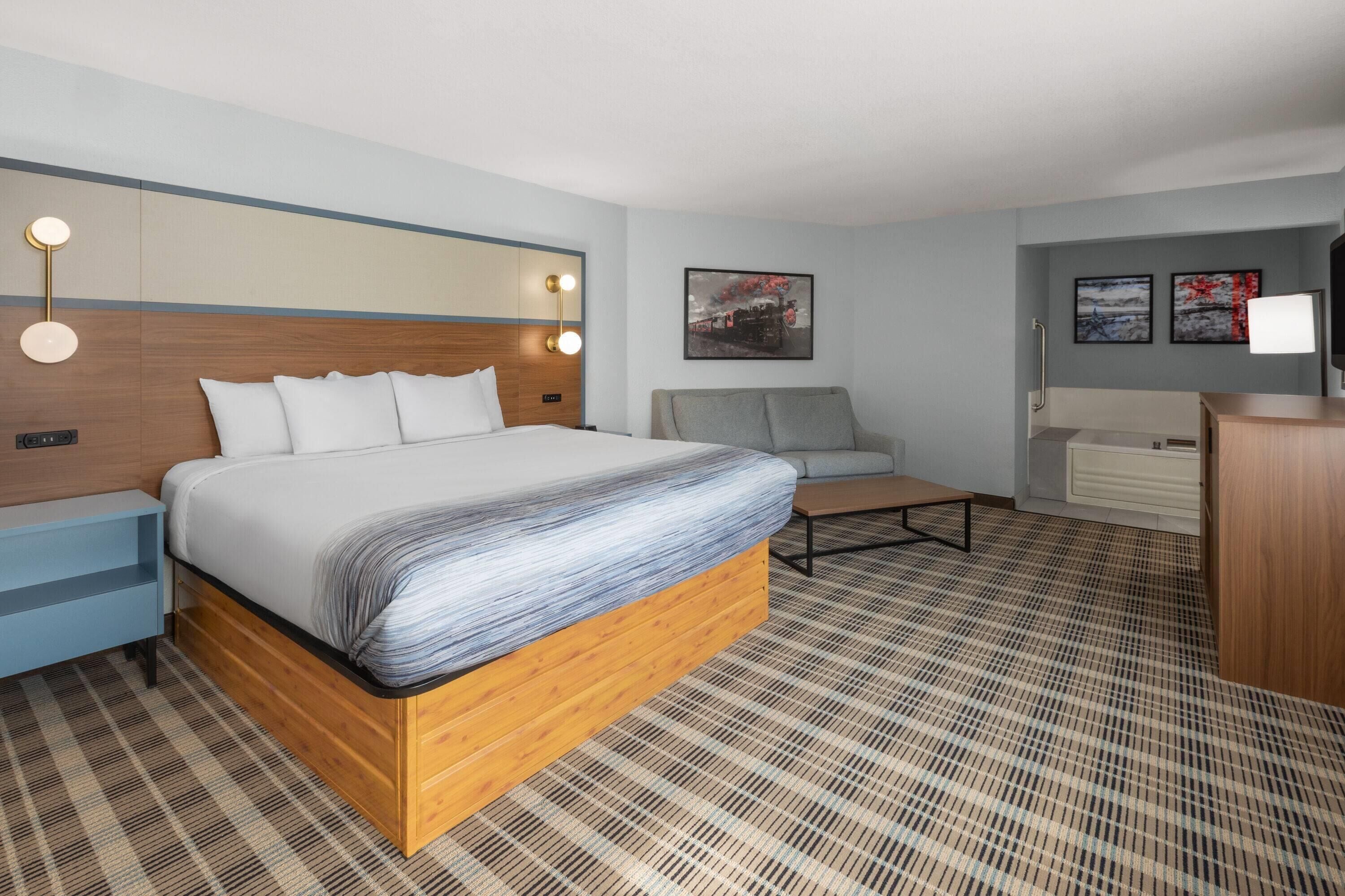 A hotel room with a large bed, a sofa, a desk, and a television.