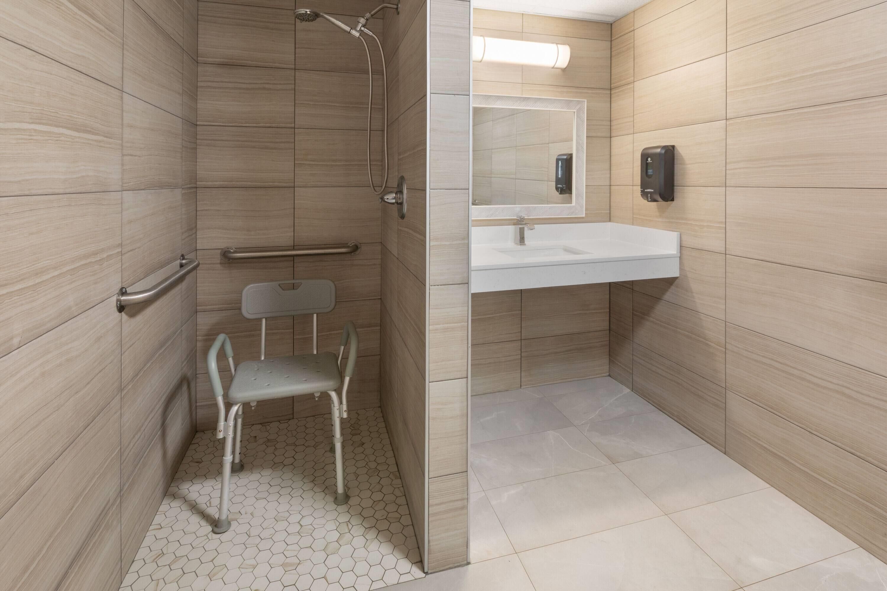 A modern bathroom with a shower, a toilet, a sink, and a mirror.