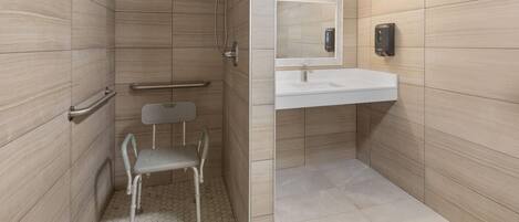 A modern bathroom with a shower, a toilet, a sink, and a mirror.