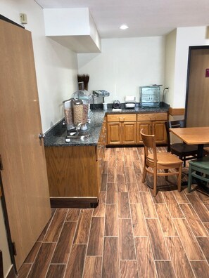 Una cocina con armarios de madera, una encimera y un comedor con sillas.