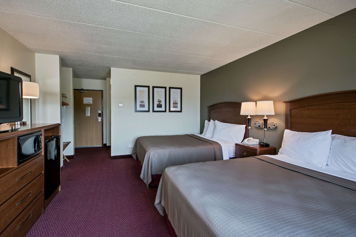A hotel room with two beds, a desk with a TV, and a microwave.