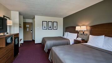 A hotel room with two beds, a desk with a TV, and a microwave.