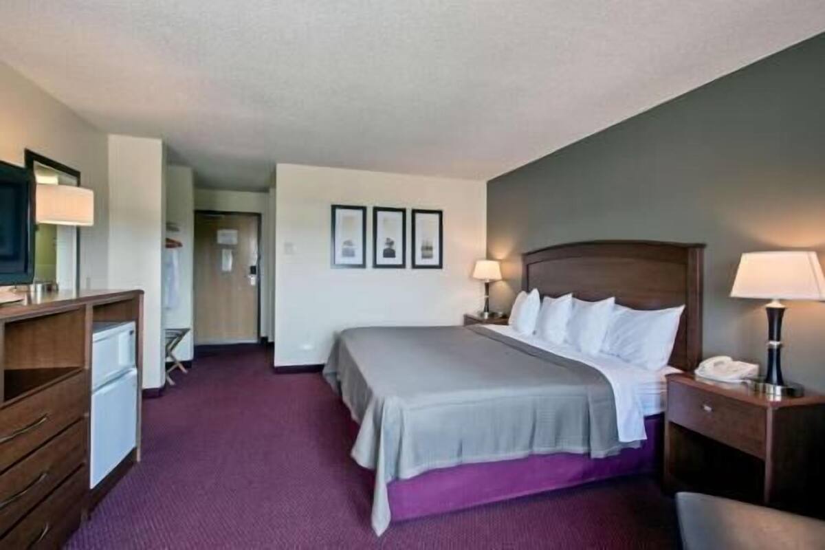 A hotel room with a bed, bedside tables, a desk, and a chair.
