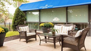A patio area with wicker furniture and a glass table, in front of a building with a blue awning labeled "SPRINGHILL SUITES Marriott". - SpringHill Suites Chicago O'Hare by Marriott (Chicago)