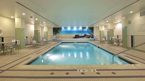 An indoor swimming pool with clear water, tiled floor, and lounge chairs. - SpringHill Suites Chicago O'Hare by Marriott (Chicago)