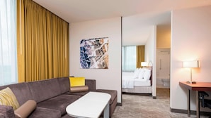 A hotel room with a sofa, a small table, a bed, and a desk with a lamp. - SpringHill Suites Chicago O'Hare by Marriott (Chicago)
