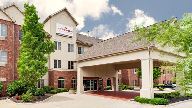 A Hawthorn Suites by Wyndham building with a brick facade, a covered entrance, and a landscaped driveway.