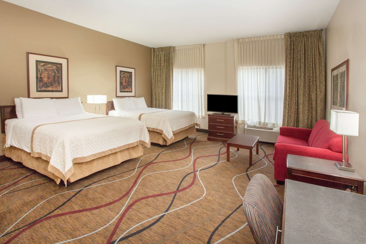 Une chambre d’hôtel avec deux lits, un canapé rouge, une télévision et un bureau.