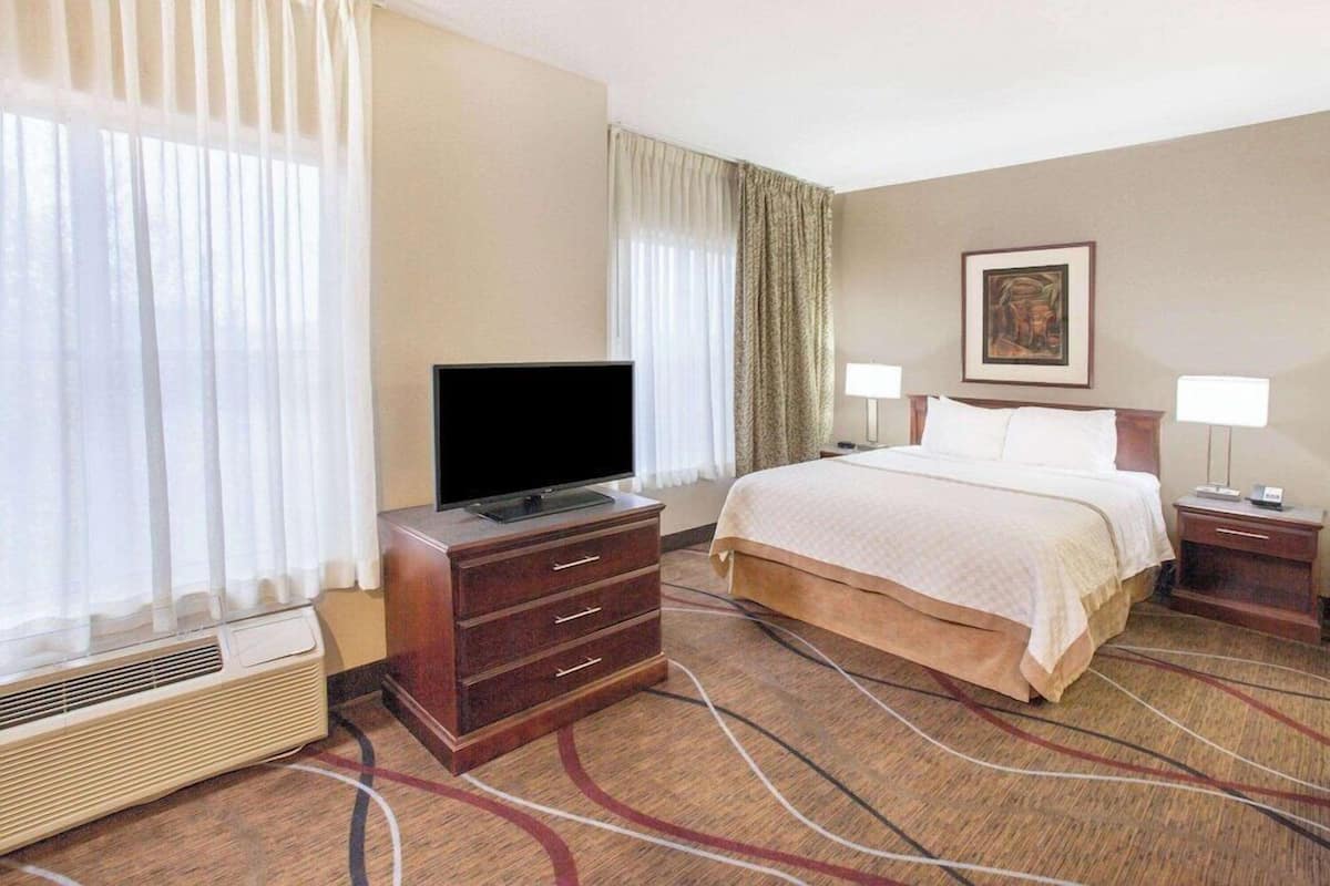Une chambre d’hôtel avec un lit, un téléviseur posé sur une commode, un radiateur et deux lampes de chevet.