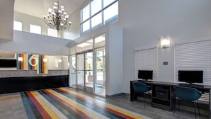 A modern hotel lobby with a colorful striped floor, a reception desk, and two computer workstations. - Studio 6 Pensacola, FL - West I-10 (Pensacola)