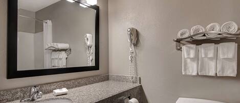 A bathroom with a granite sink, a mirror, a hairdryer, and a toilet.