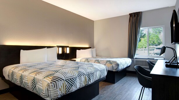 A hotel room with two beds, a desk, and a chair. - Studio 6 Pensacola, FL - West I-10 (Pensacola)