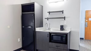 A compact kitchenette with a black refrigerator, a microwave, a coffee maker, and a sink. - Studio 6 Pensacola, FL - West I-10 (Pensacola)