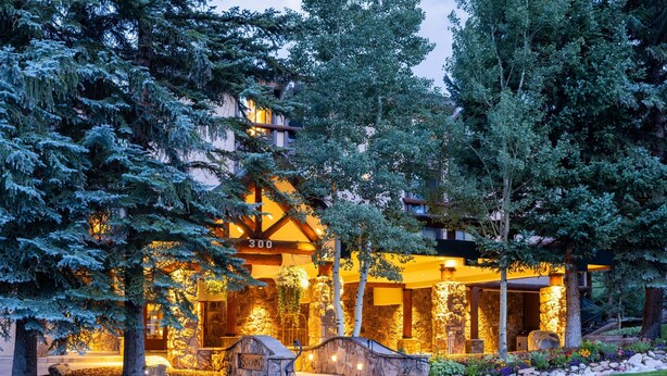 A lodge with a stone facade, wooden beams, and a stone entrance. - Stonebridge Inn (Snowmass Village)