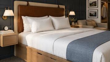 A hotel room with a large bed, bedside tables, a nightstand, a dresser, and a wardrobe.