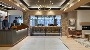 A modern lobby with a reception desk, bar area, and seating. - Stonebridge Inn (Snowmass Village)