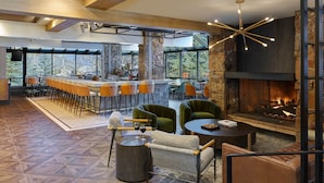 A spacious indoor area with a bar, seating, and a fireplace. - Stonebridge Inn (Snowmass Village)