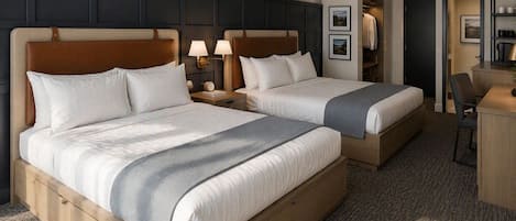 A hotel room with two beds, a desk, a chair, and a wardrobe.