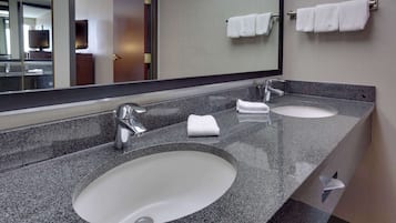 Casa de banho moderna com duas pias, um espelho grande e um porta-toalhas com vários toalhos.