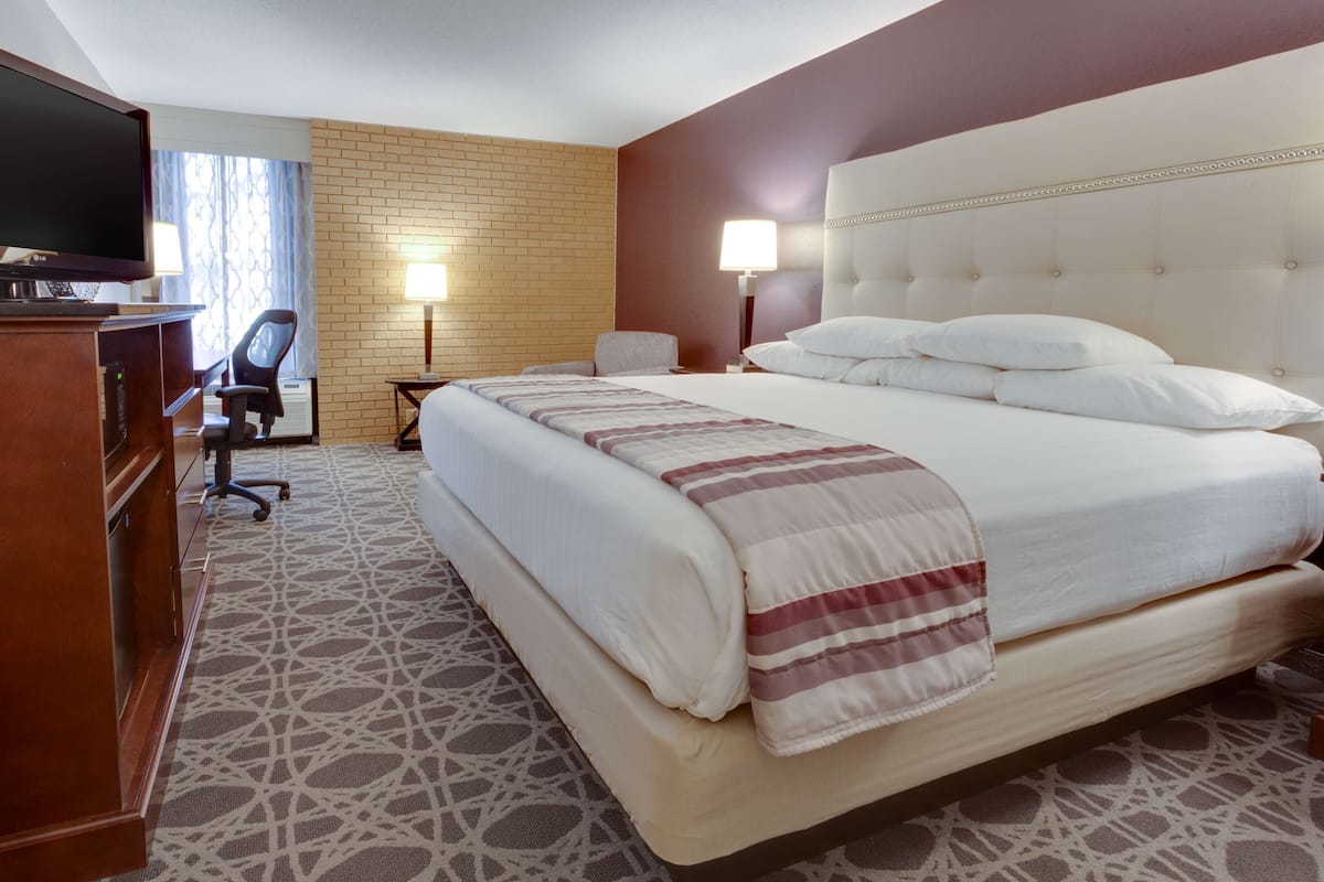 A hotel room with a large bed, a desk with a computer, a chair, and a TV.
