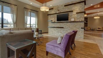 A modern living room with a stone accent wall, a flat-screen TV, and a wooden ceiling.