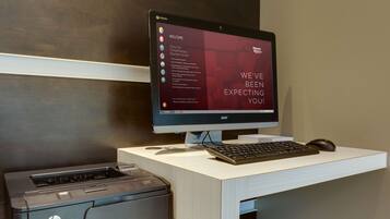 A desktop computer with a monitor, keyboard, and mouse on a desk. There is an HP printer on the desk.